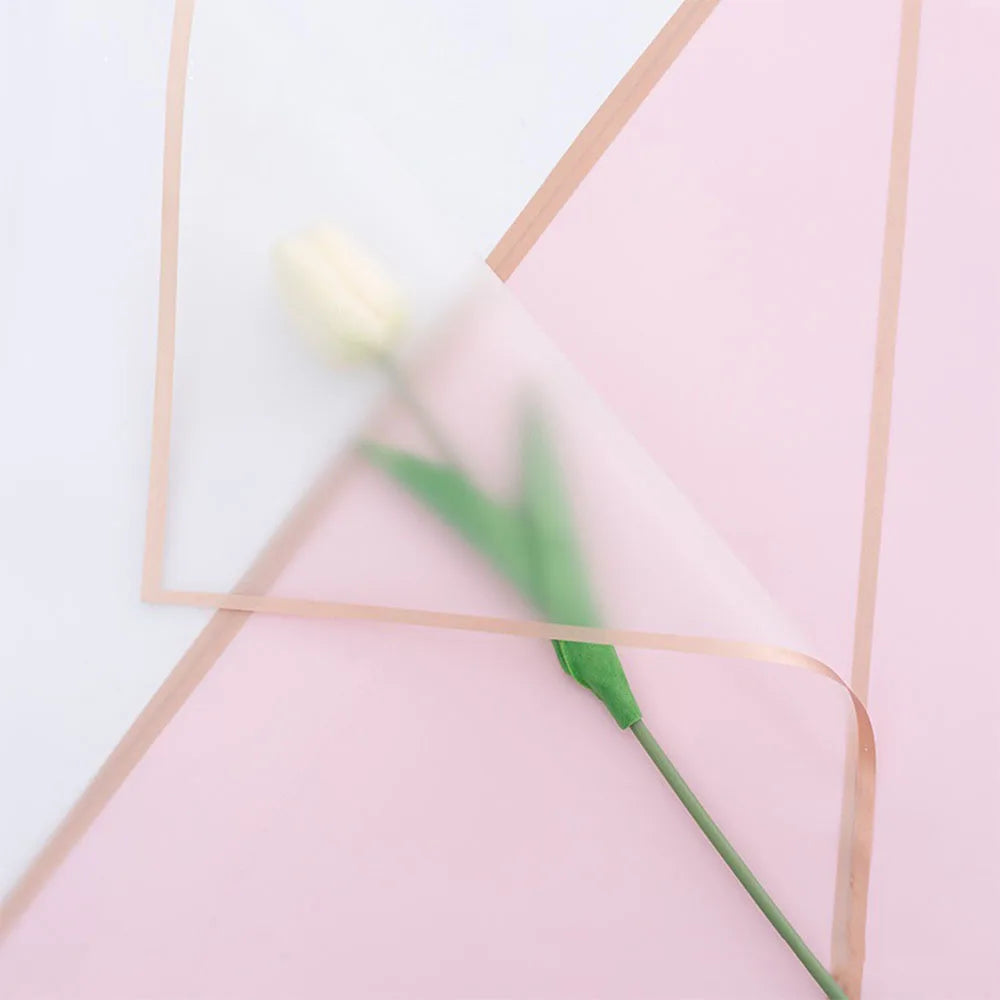 A pale yellow tulip is visible within a pink paper fold with gold edge wrapping.