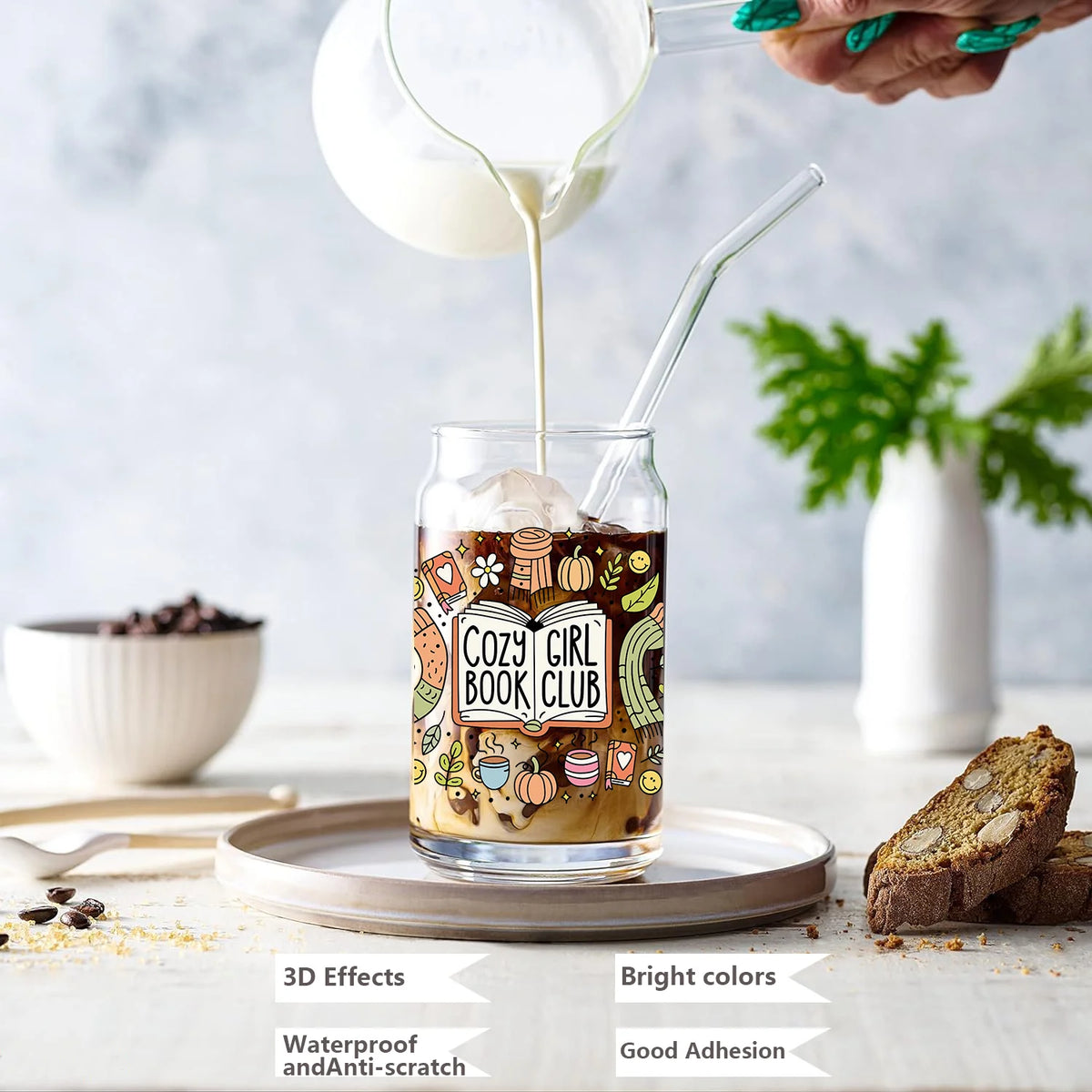 A hand pours milk into a glass filled with ice and decorative stickers for a cozy girl book club theme.
