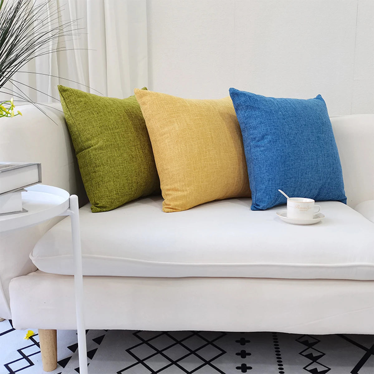 Two solid color linen pillows, one olive green and one mustard yellow, resting on a white sofa.