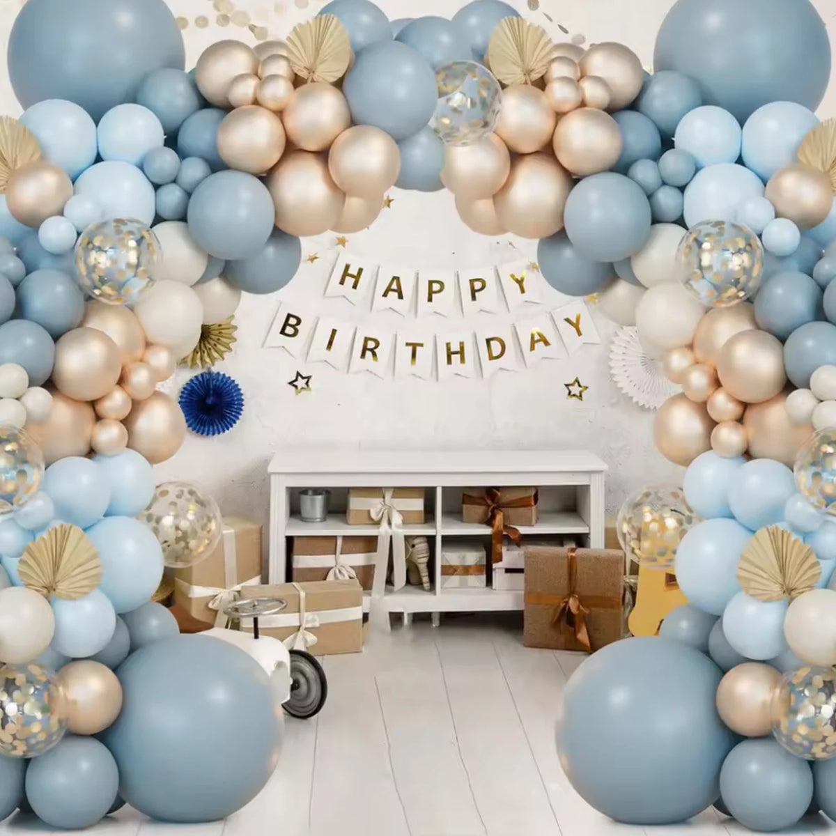 A large balloon arch decoration featuring blue, sand, white, and gold latex balloons for a birthday celebration.