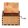 A wooden music box with a sun design and an engraved lid, featuring a hand crank mechanism.