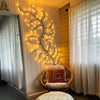 A decorative wall light featuring a branch of LED willow vine lights illuminating a cozy corner.
