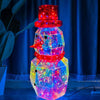A colorful prismatic LED snowman decoration with glowing lights standing in front of a blue curtain.