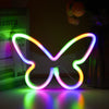 A glowing neon sign shaped like a butterfly with rainbow colored light on a surface.