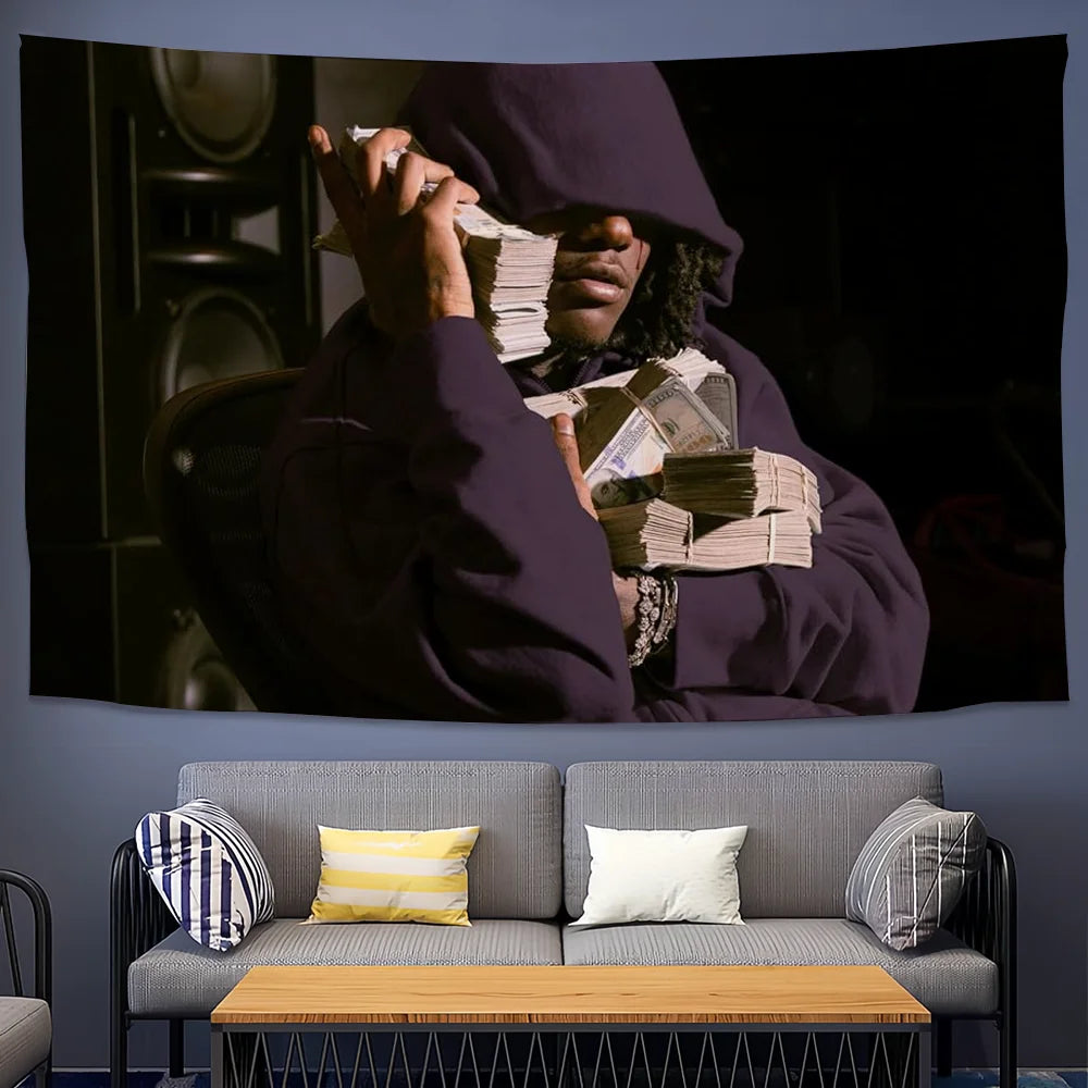 A portrait of a person wearing a dark hoodie holding stacks of cash against a dark background.
