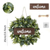 Artificial eucalyptus wreath with green leaves and a wooden welcome sign hanging on a wire.