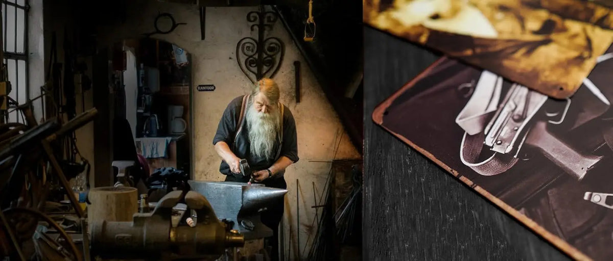 A bearded man in a dark shirt is working on metal tin signs in a dimly lit workshop.