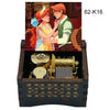 A hand-cranked wooden music box featuring an illustration of a couple in historical attire.