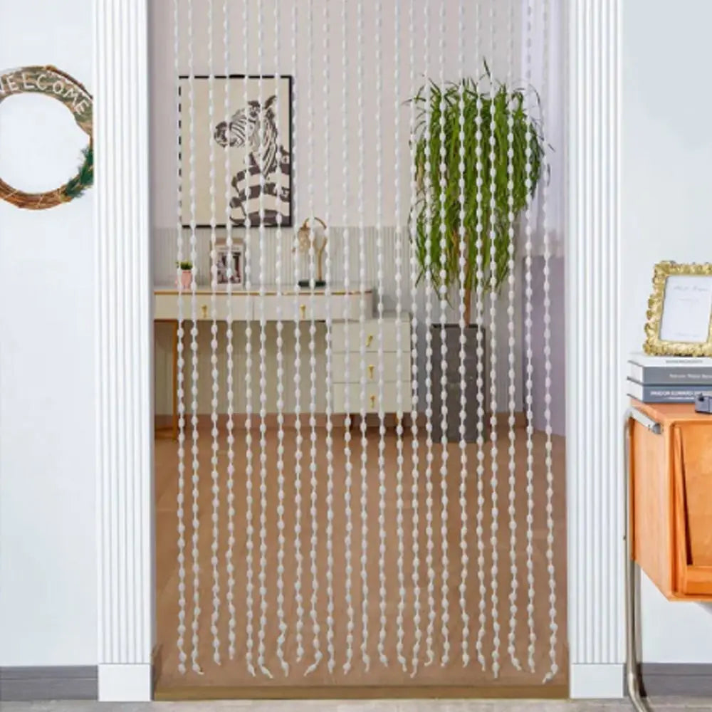 Elegant beaded string curtain with tassels used as a bohemian drape in a doorway.