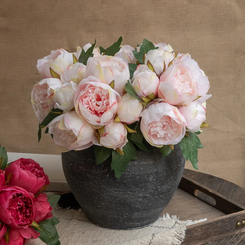 A bouquet of elegant artificial silk peonies in shades of pink and white displayed in a dark vase.