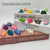A collection of 12 random colored articulated baby dragon figurines displayed on a wooden box.