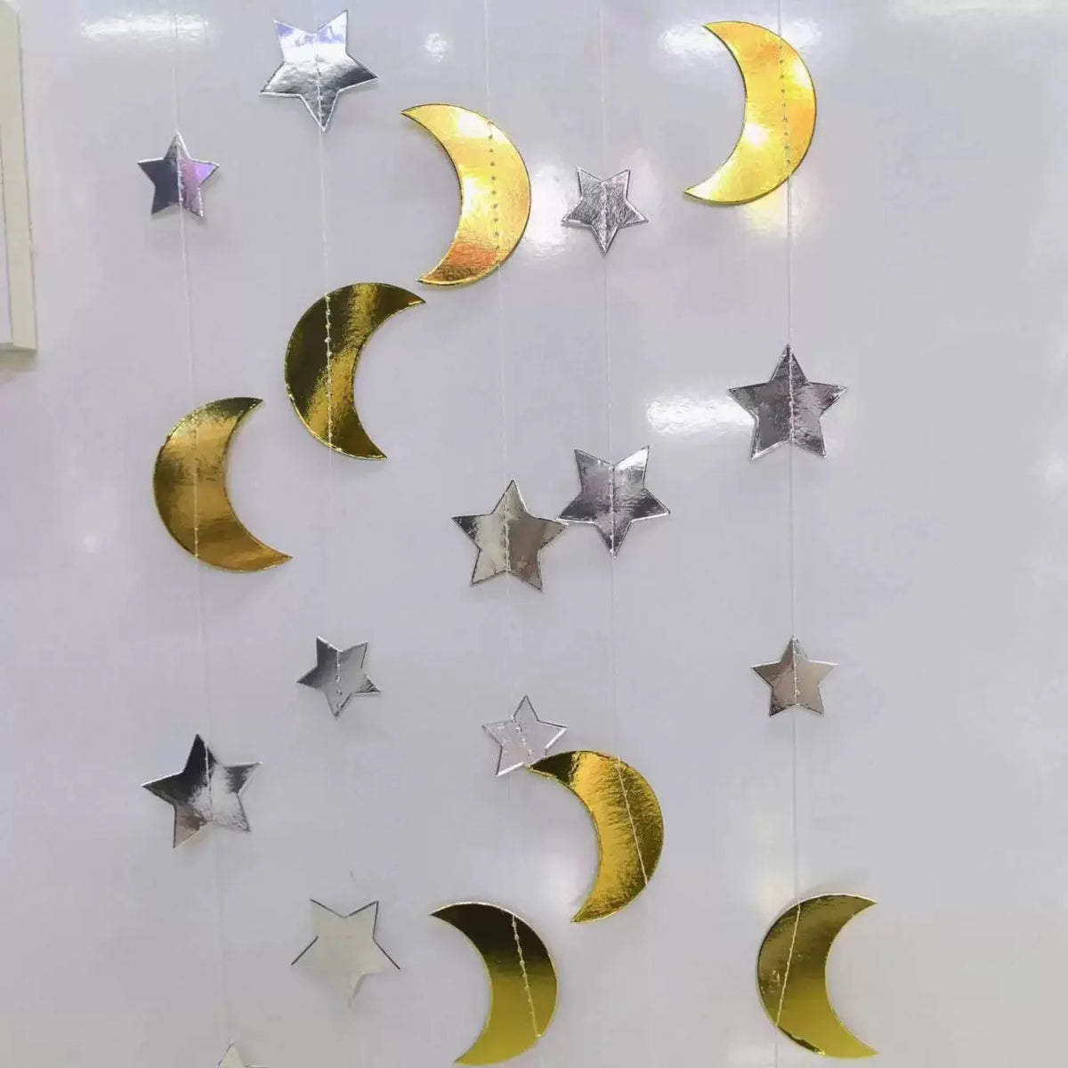 A vertical display of metallic gold and silver star and crescent moon shapes used for a party bunting.