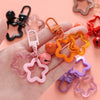 A hand holds various colorful star charm pendants and keychains made of plastic and metal.