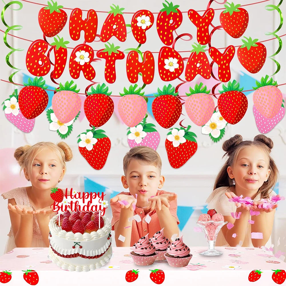 A strawberry birthday party decoration set featuring a banner, cake toppers, and cupcakes on a table.