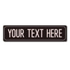 A black rectangular metal sign with the text YOUR TEXT HERE in white capital letters.