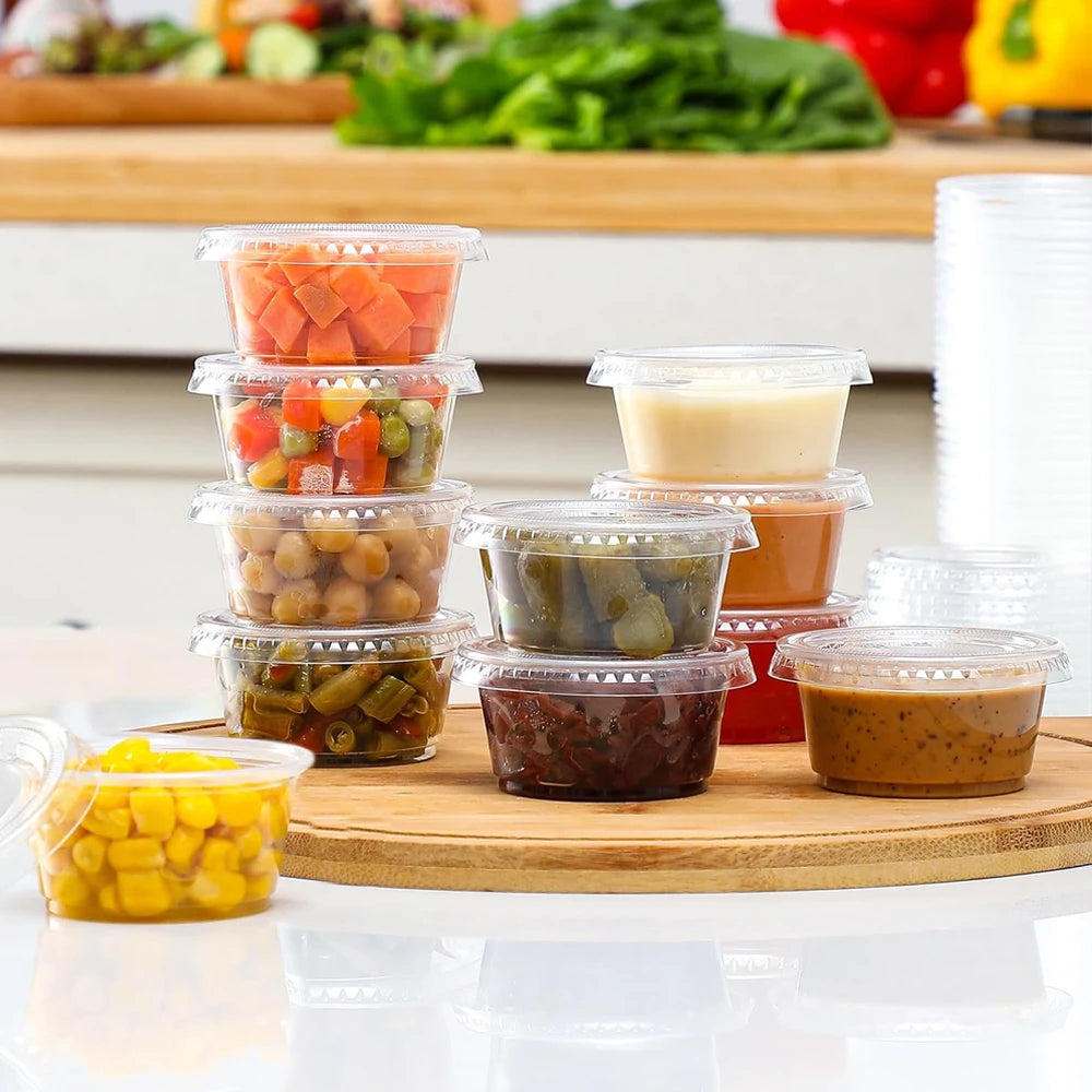 Une collection de purées colorées dans des gobelets en plastique transparent disposés sur une planche en bois.