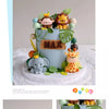 A tiered cake decorated with jungle animal toppers including a monkey, lion, and elephant.