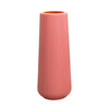 A tall, cylindrical plastic flower vase with vertical ribbed texture in a soft coral pink color.