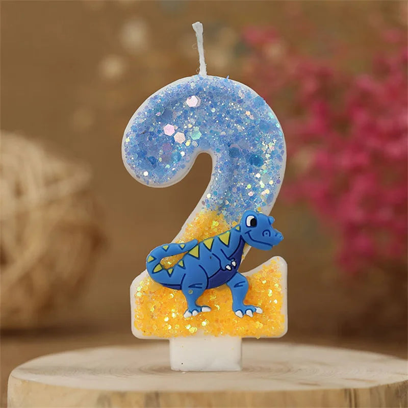 A birthday candle shaped like the number 2, decorated with blue glitter and a small dinosaur figure.