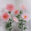 A large artificial silk pink poppy flower arrangement displayed on a green stand against a white background.