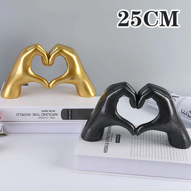 Gold heart-shaped resin hand sculpture resting on a stack of books.