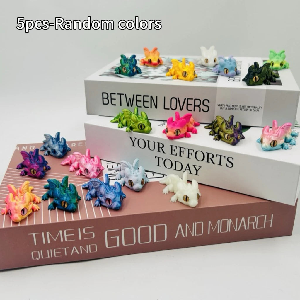 A collection of five random colored articulated baby dragon figurines displayed on a wooden box.