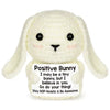 A handmade white crochet bunny doll with long ears and an inspirational card attached.