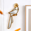 Gold resin animal wall hanging decor shaped like a bird mounted on a white wall.