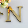 A 3D golden letter N made of mirror material resting on a white surface.