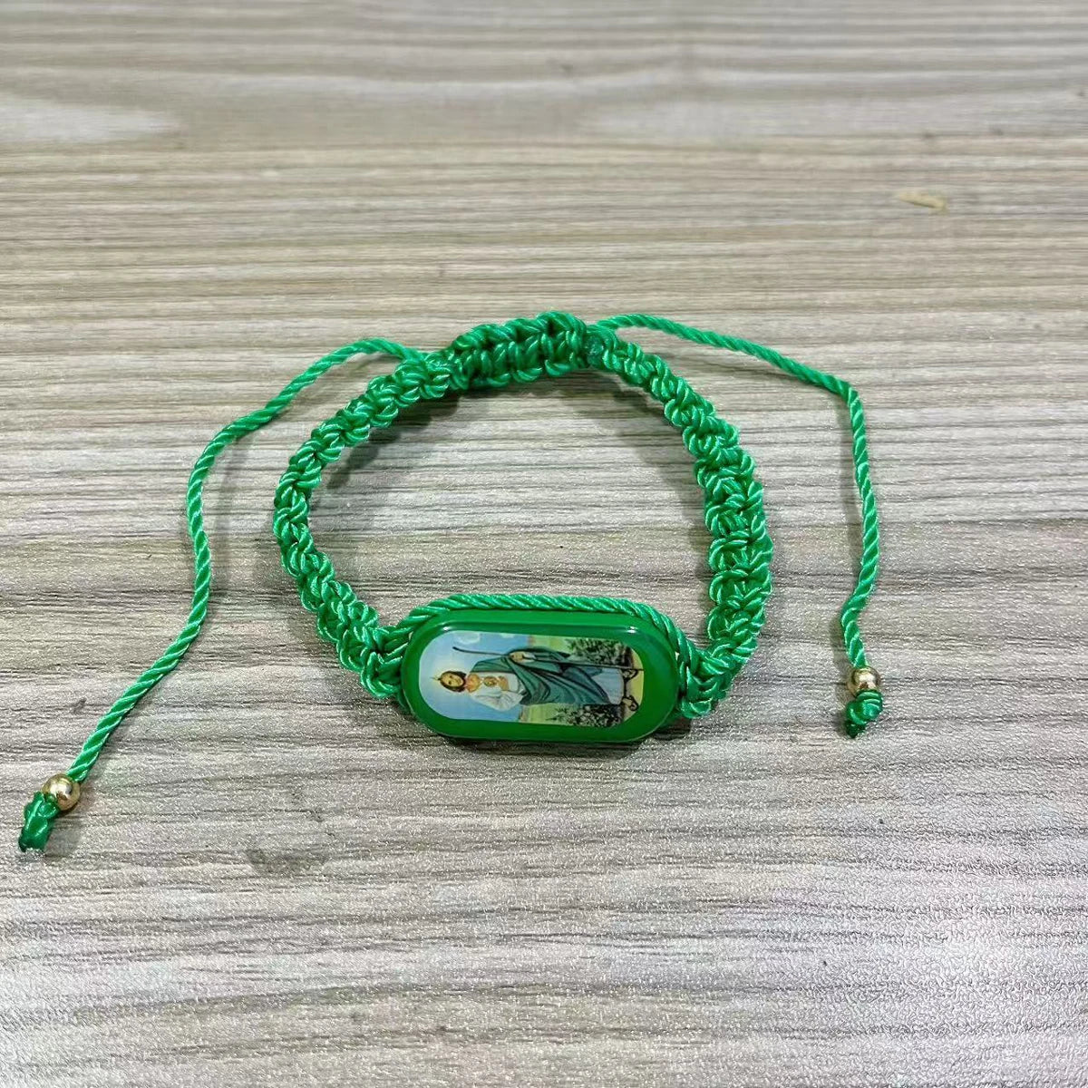 A green beaded bracelet with a rectangular pendant featuring a depiction of the Virgin Mary.