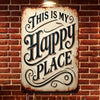A rustic iron wall sign with carved text that reads This Is My Happy Place mounted on a brick wall.