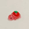 A small, bright red resin charm shaped like a fruit turtle with green leaves.