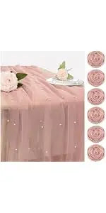 A set of vintage bud glass vases in a dusty rose color displayed on a draped fabric.
