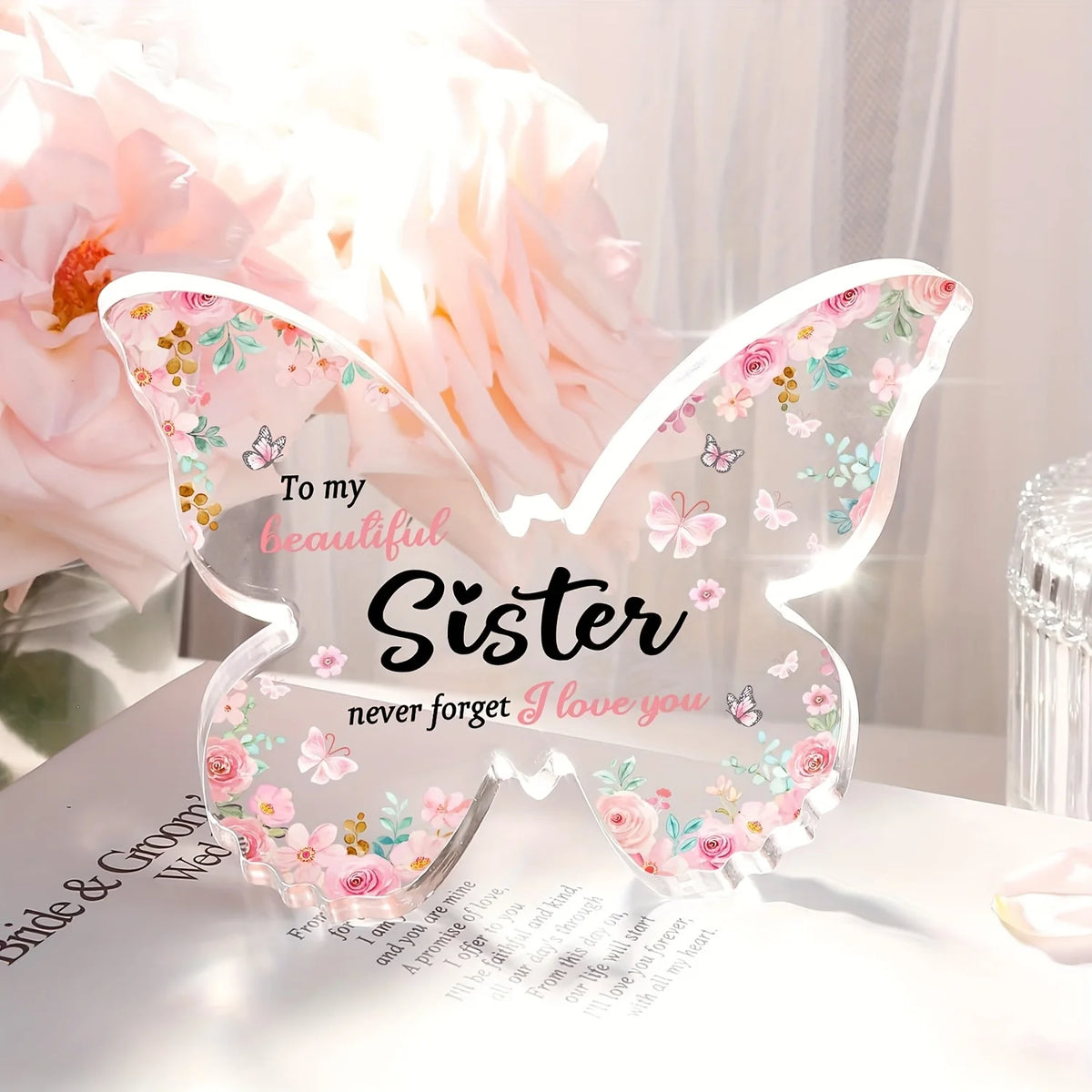 A clear butterfly-shaped acrylic keepsake gift with pink and floral designs for a sister or best friend