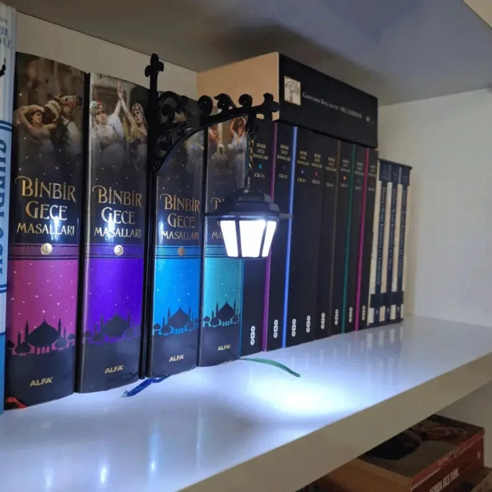 A display of vintage books and a lantern lamp on a white shelf.