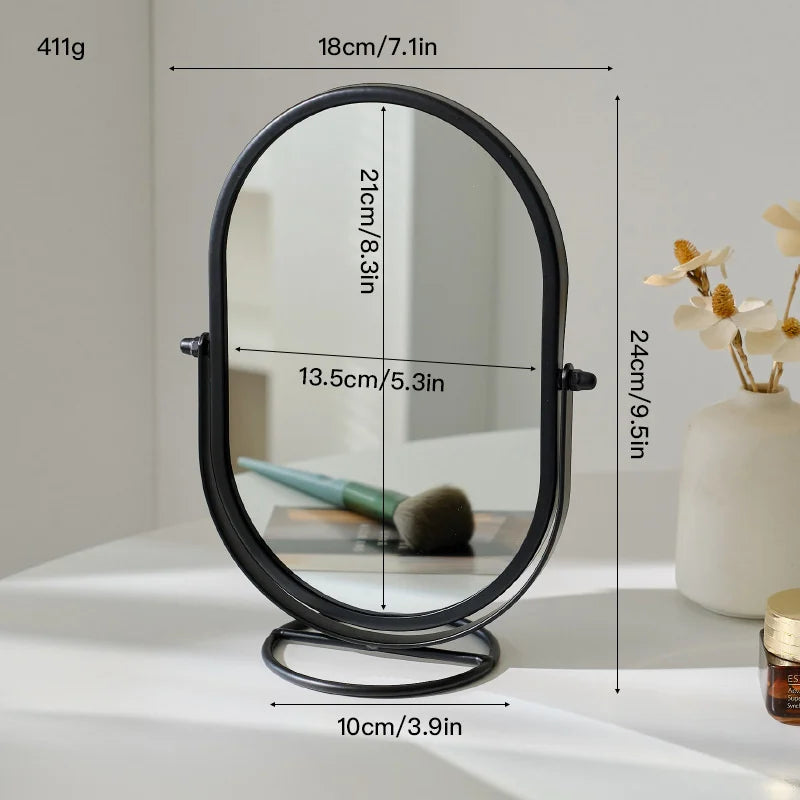 A black oval vanity mirror with a rotating base, shown on a white surface.