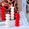 A set of red and white silicone candle molds with lit candles displayed on a white surface.