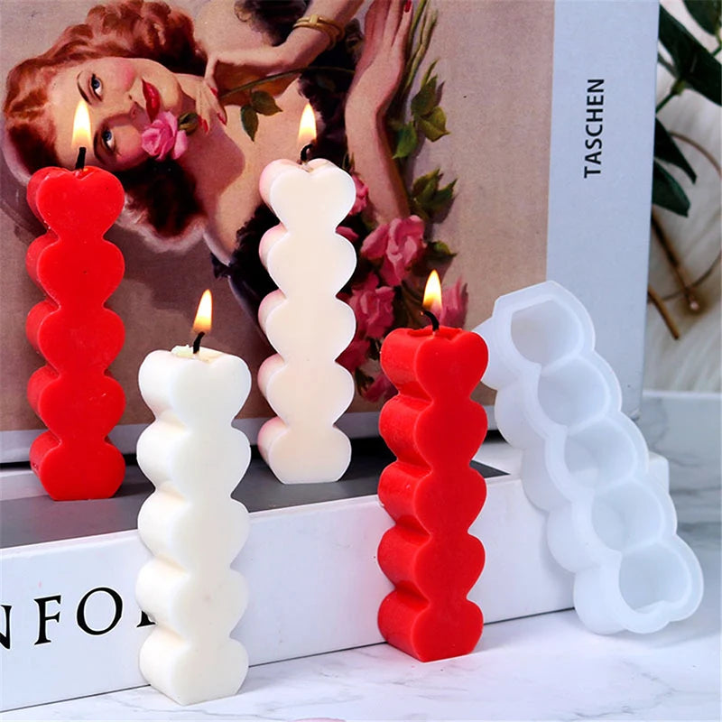A set of red and white silicone candle molds with lit candles displayed on a white surface.