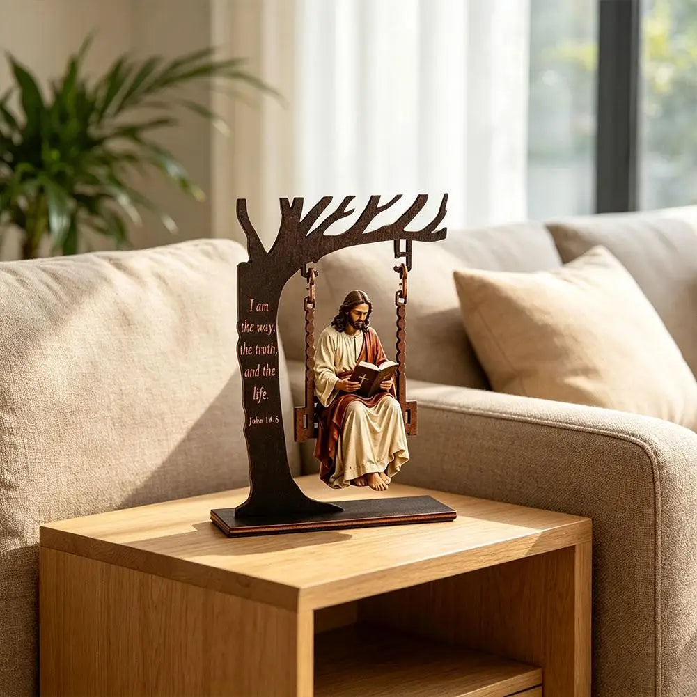 Wooden silhouette of a tree with Jesus sitting on a swing, featuring a Bible verse, displayed on a wooden table.