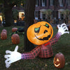 An inflatable Halloween pumpkin decoration shaped like a person with a plaid shirt and white gloves lying on grass.