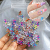 A hand holds a clear plastic bag filled with a 50-pack of colorful 3D resin ladybug nail art charms.