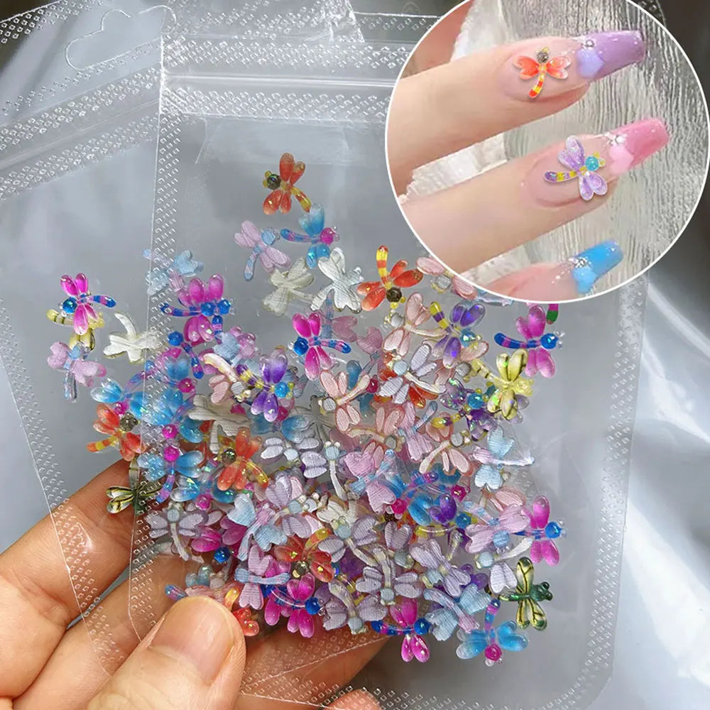 A hand holds a clear plastic bag filled with a 50-pack of colorful 3D resin ladybug nail art charms.