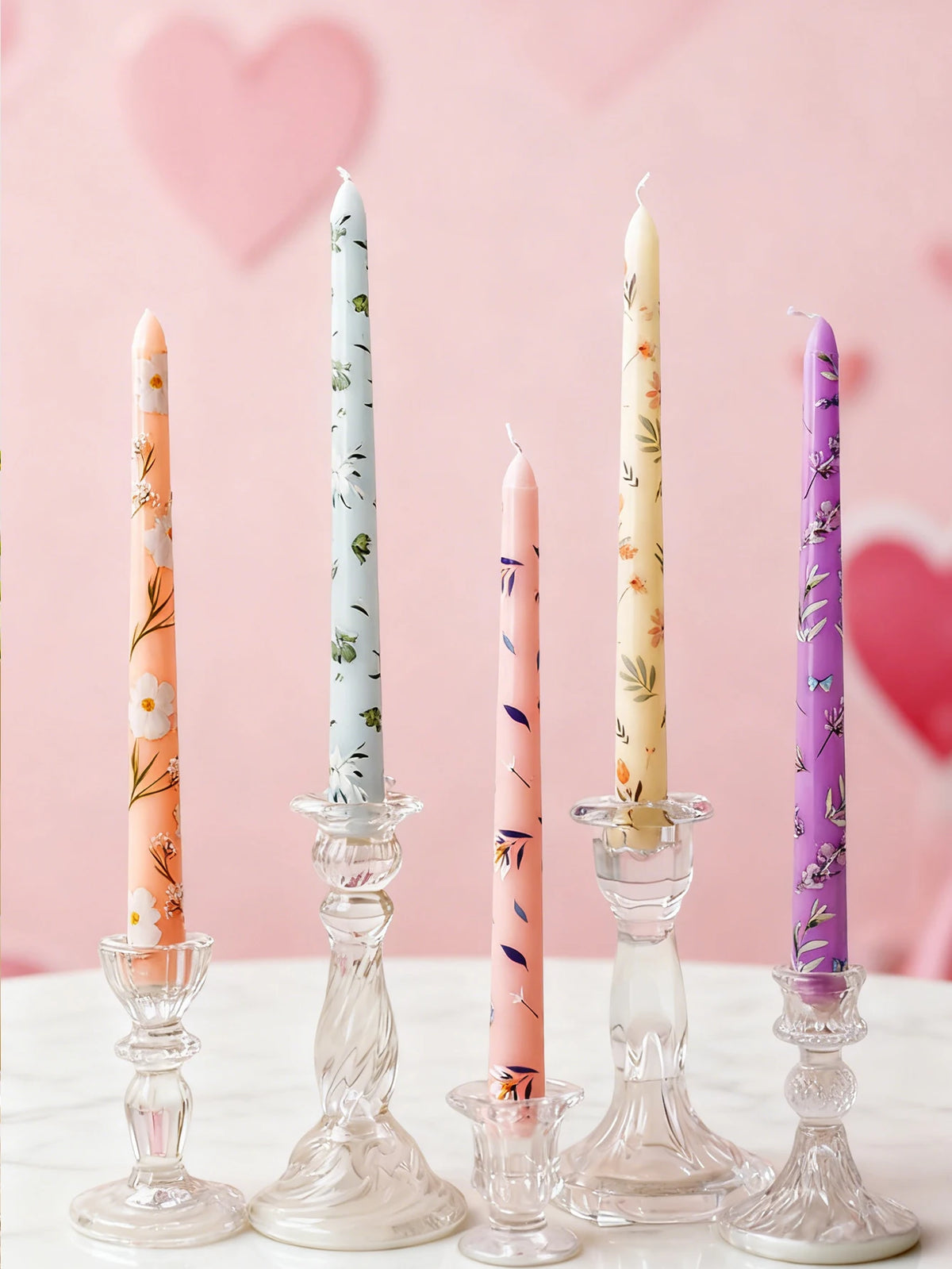 A collection of tall, decorative printed candles in peach, mint green, and lavender on a white surface.