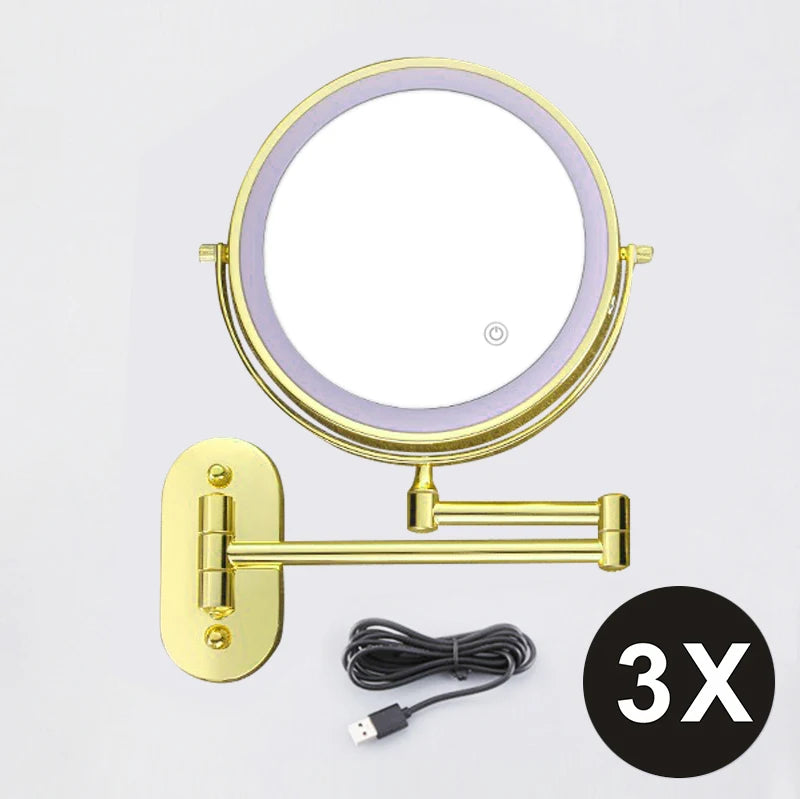 A round, illuminated magnifying makeup mirror with a gold frame and USB charging cable.