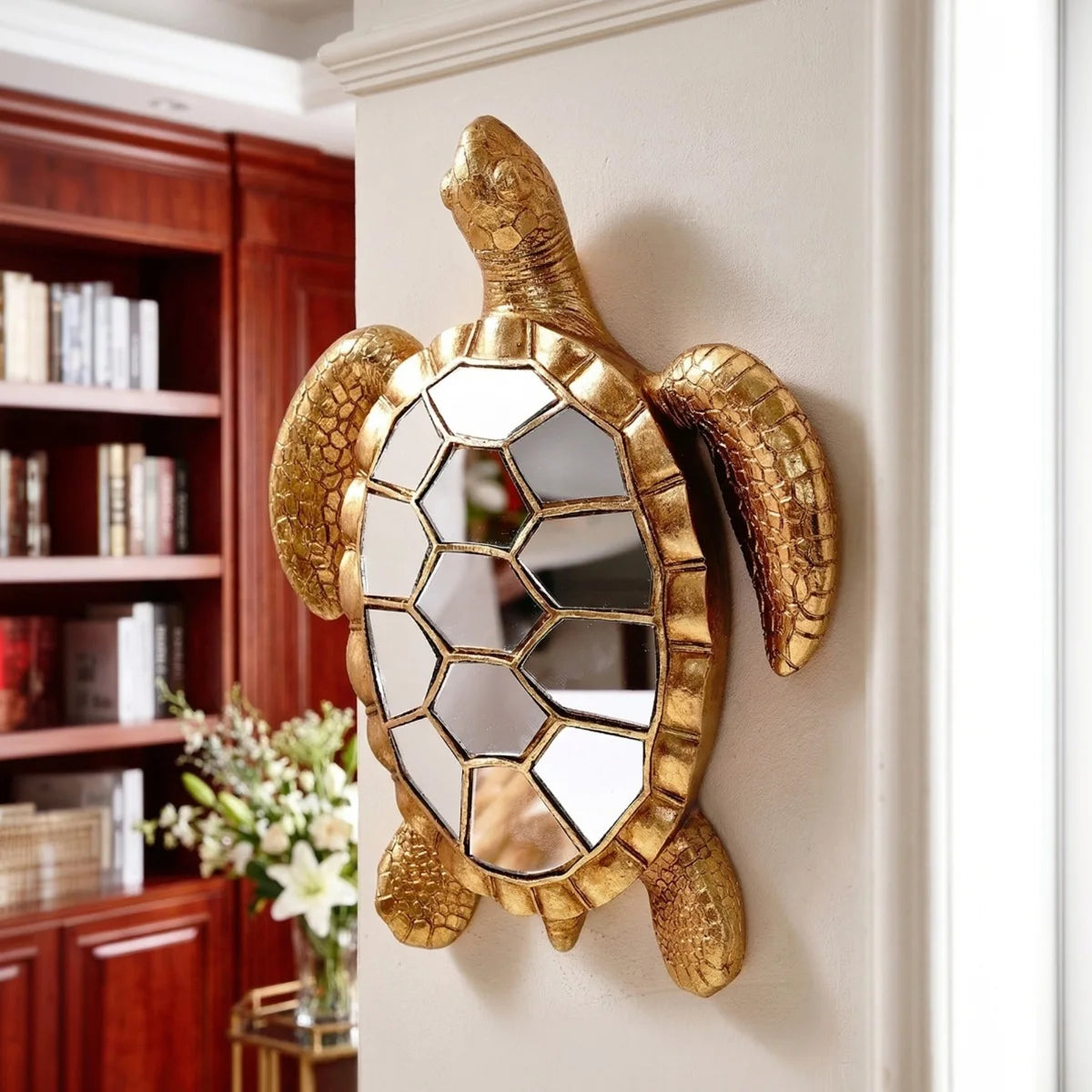 A golden sea turtle resin wall decor mirror mounted on a white wall.