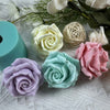 A collection of pink, white, and green silicone rose molds and floral elements on a white textured surface.