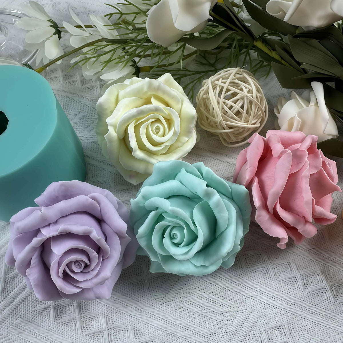 A collection of pink, white, and green silicone rose molds and floral elements on a white textured surface.