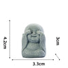 A smooth, gray stone statue of a monk with hands covering his face, used for meditation or Zen decor.