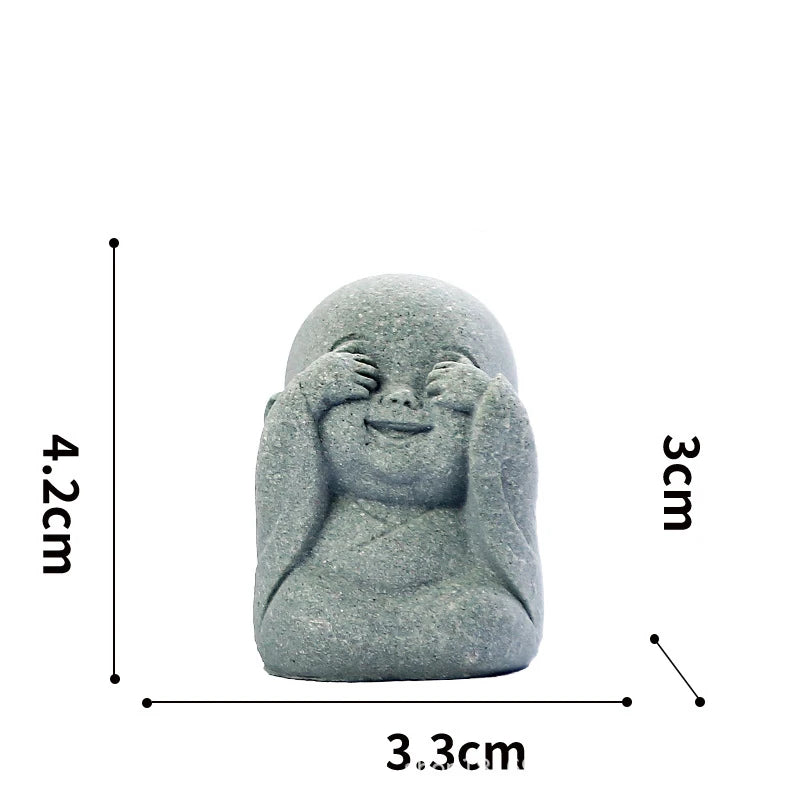 A smooth, gray stone statue of a monk with hands covering his face, used for meditation or Zen decor.