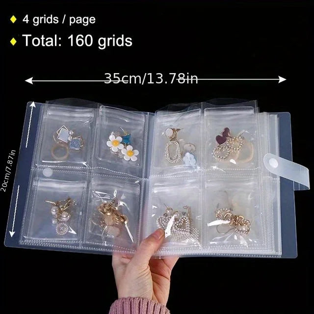 A hand holds an open transparent jewelry organizer storage bag showing multiple compartments for storing jewelry.